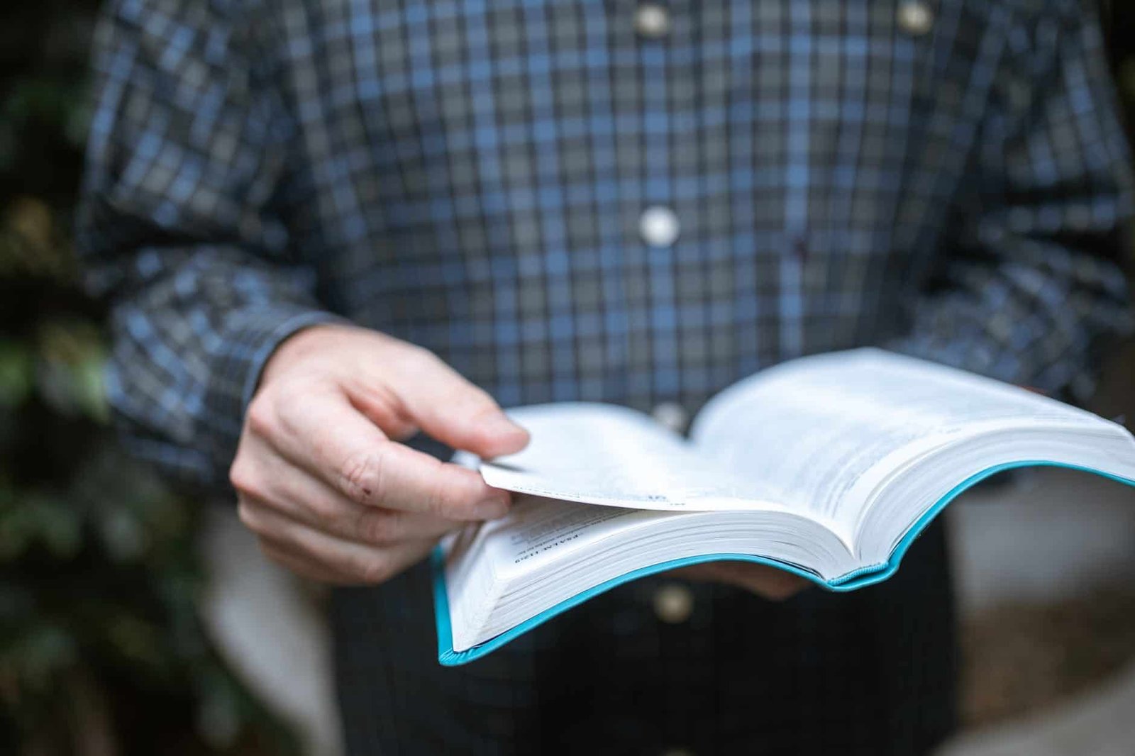 person in blue and white plaid long sleeve shirt holding white paper