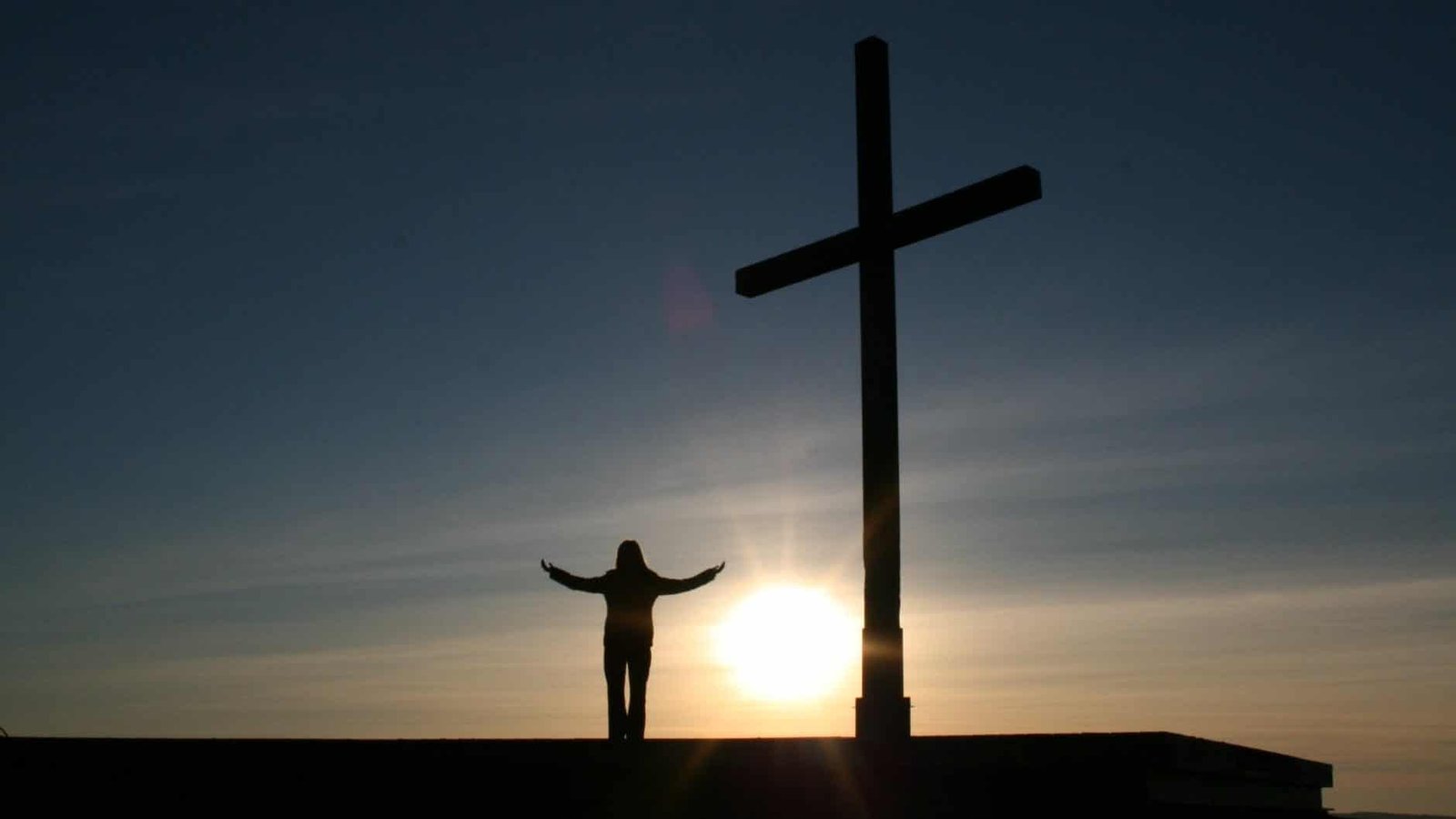 silhouette of person standing beside cross during sunset. God is the most generous person I know.