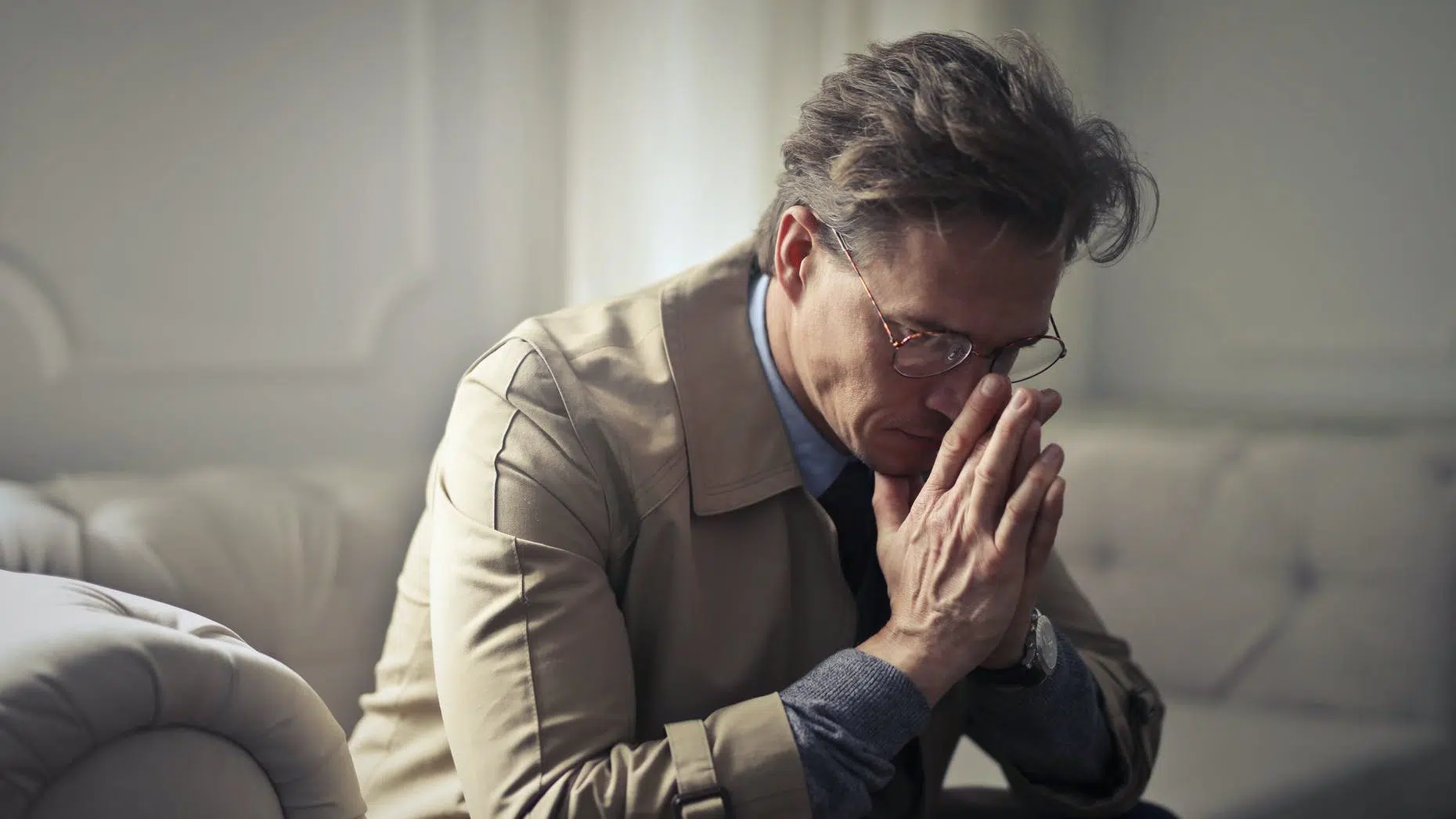 sad mature businessman thinking about problems in living room. Prayer to make ends meet.