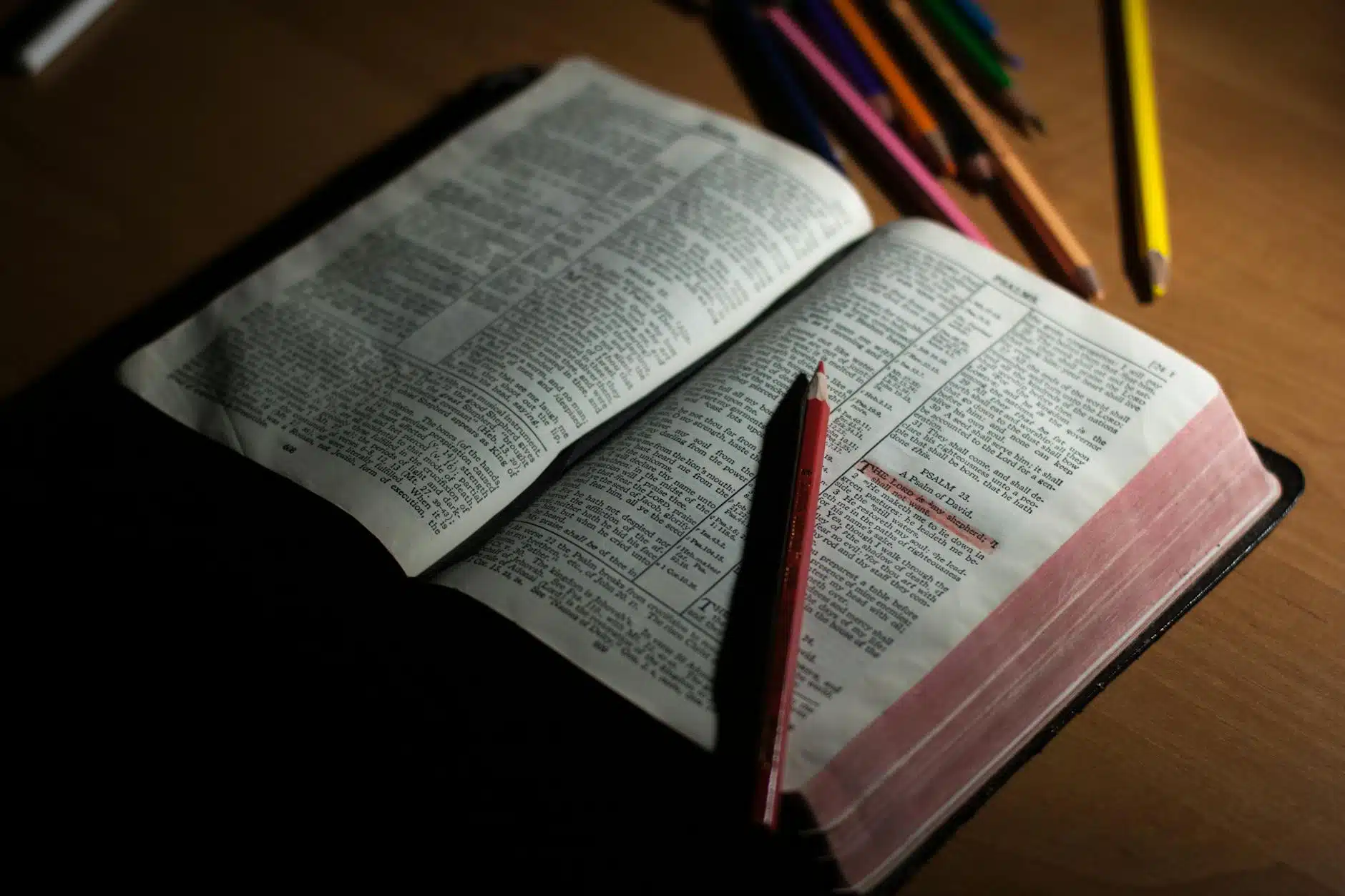 pink pencil on open bible page and pink