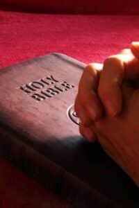person hands on holy bible