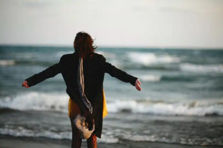 person standing on beach with open arms
