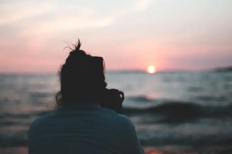 woman in white shirt standing near sea during sunset