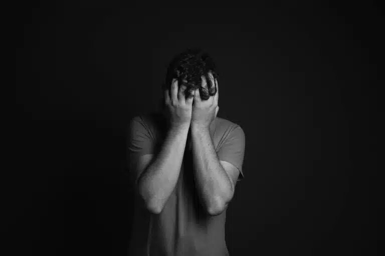 gray scale photo of man covering face with his hands