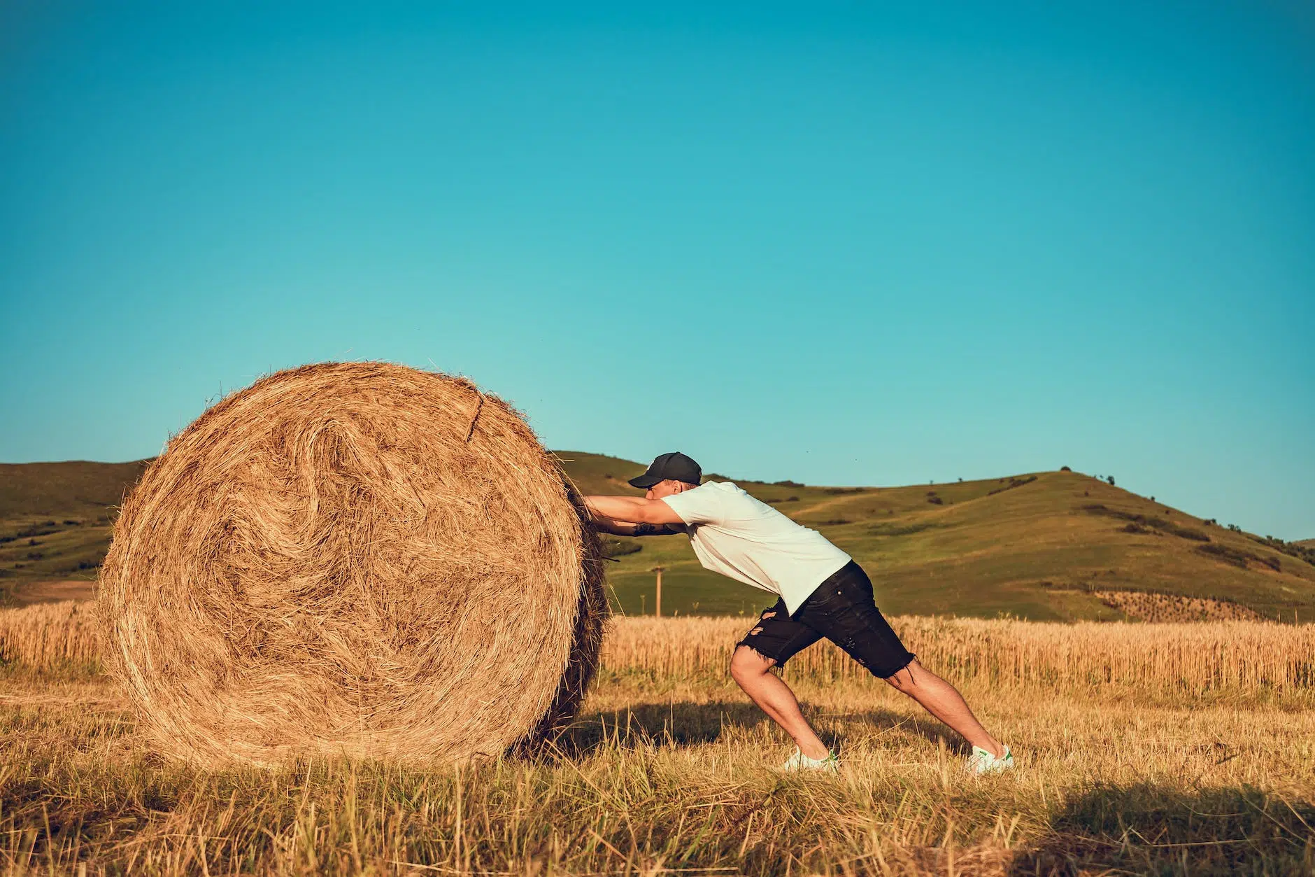 photo of man pushing hay bale