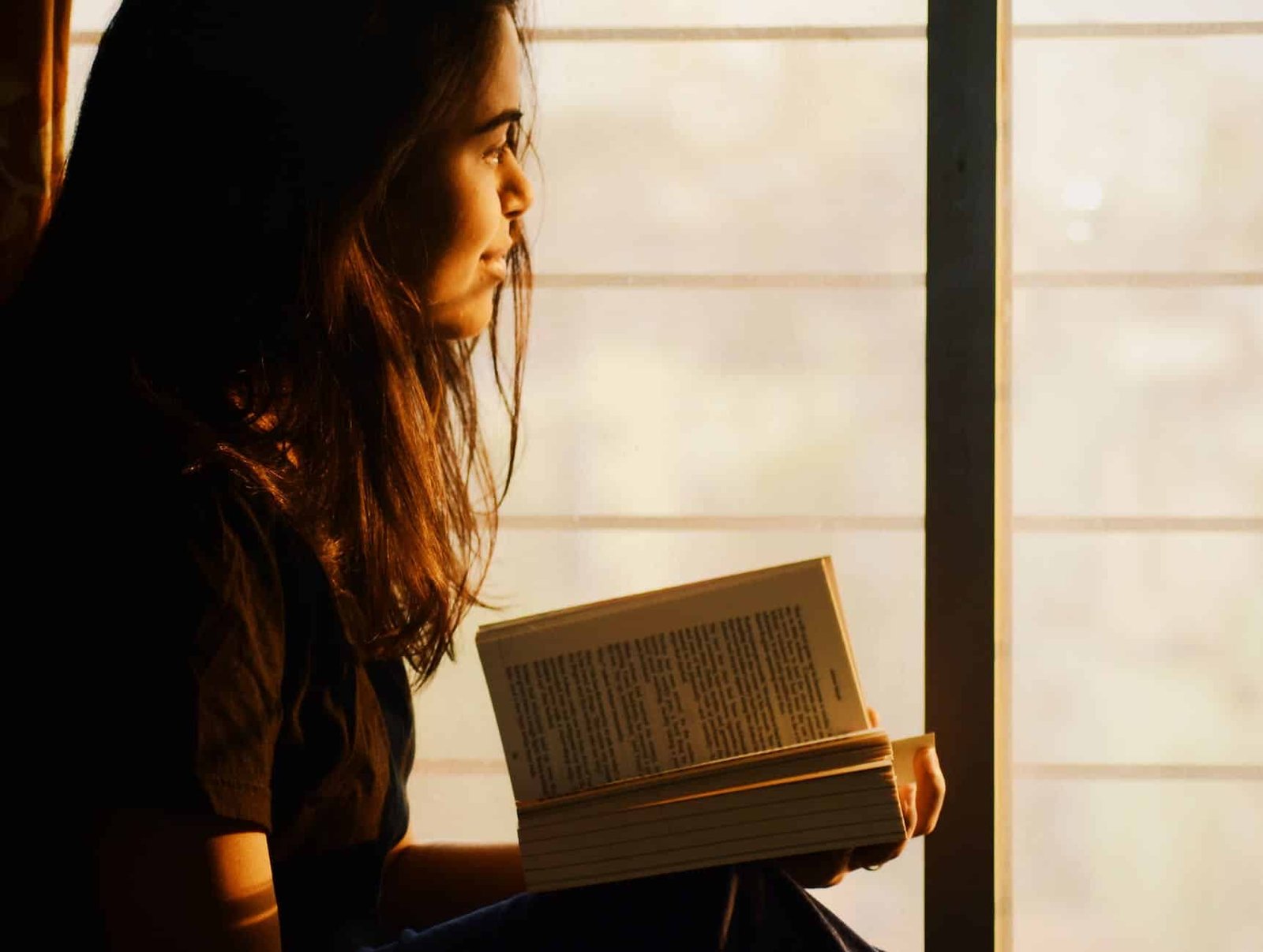 woman reading book on window