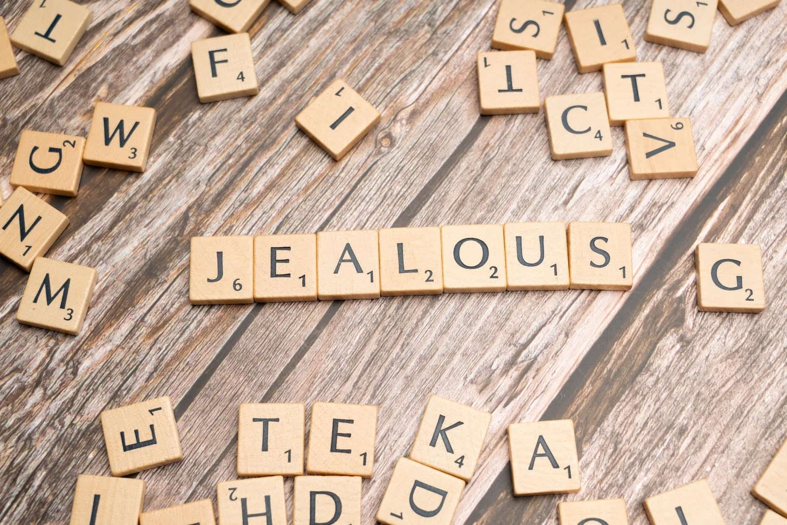 scrabble letters spelling jealous on a wooden table