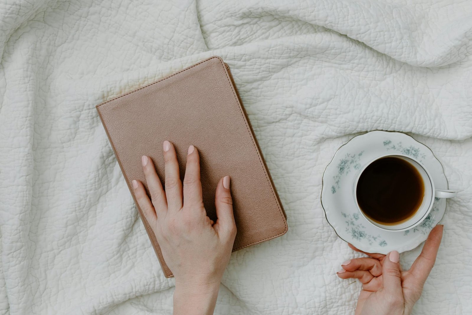 a person holding a book beside the coffee cup