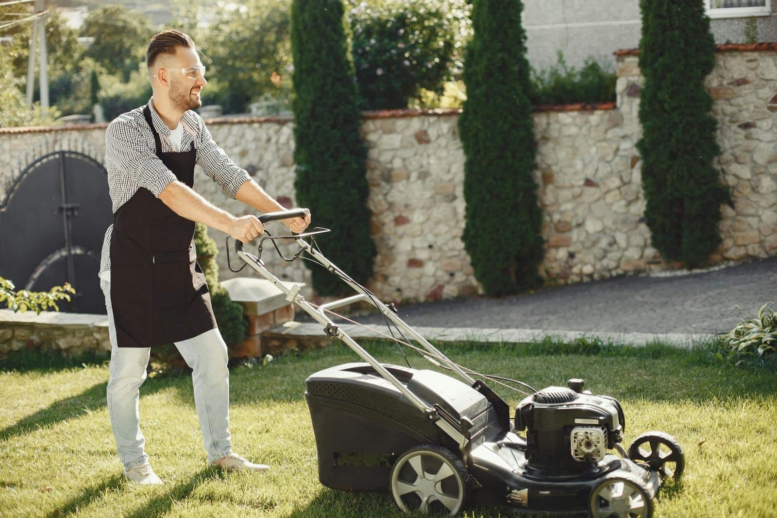 woman in white and black long sleeve shirt holding black and gray lawn mower