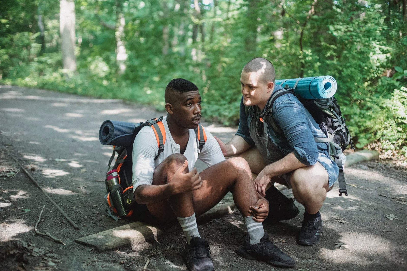 black exhausted tourist resting on ground with friend