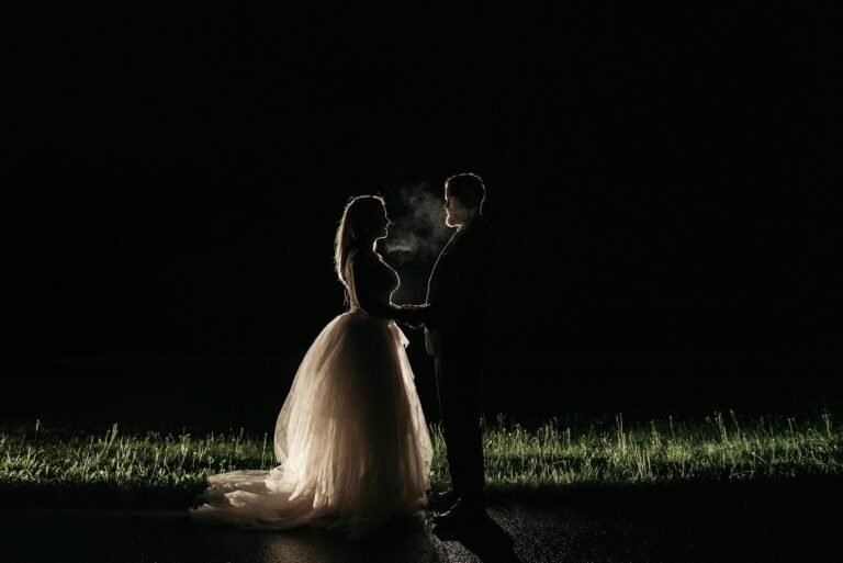 a newlywed couple standing face to face under dark sky