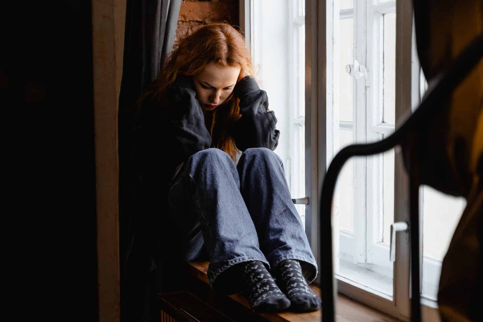 depressed woman sitting by the window