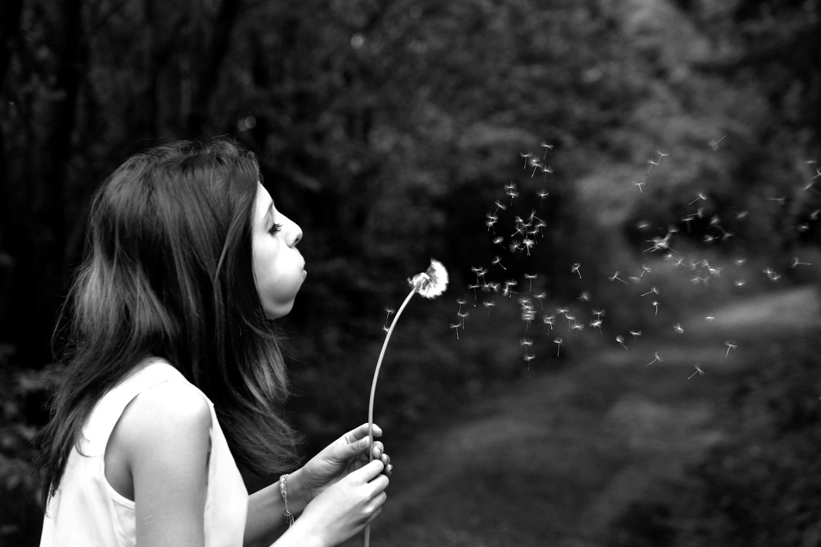 woman in tank top blowing dandelion in grayscale photography