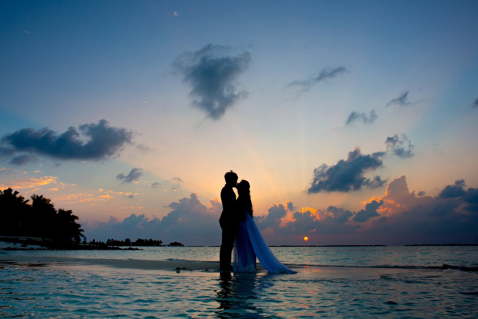 silhouette photo of man and woman kisses between body of water