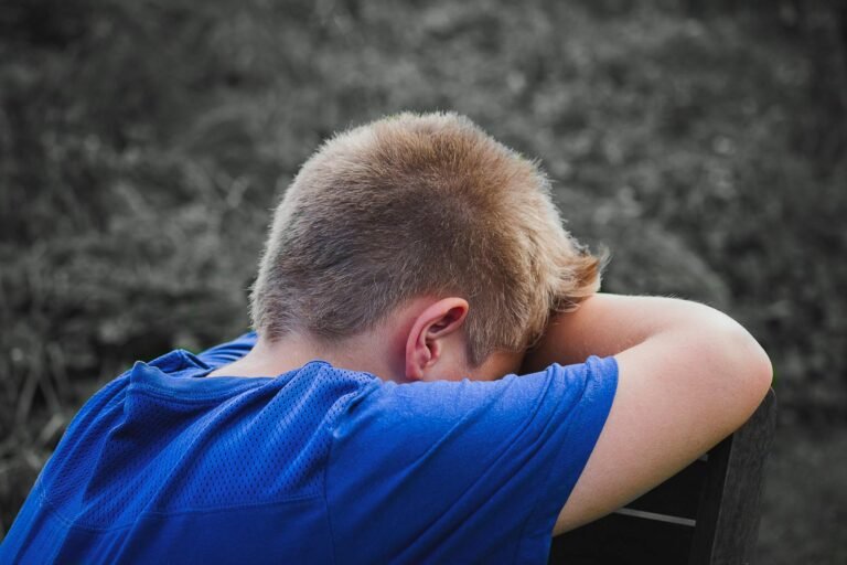 close up photo of sad child leaning on a wooden chair