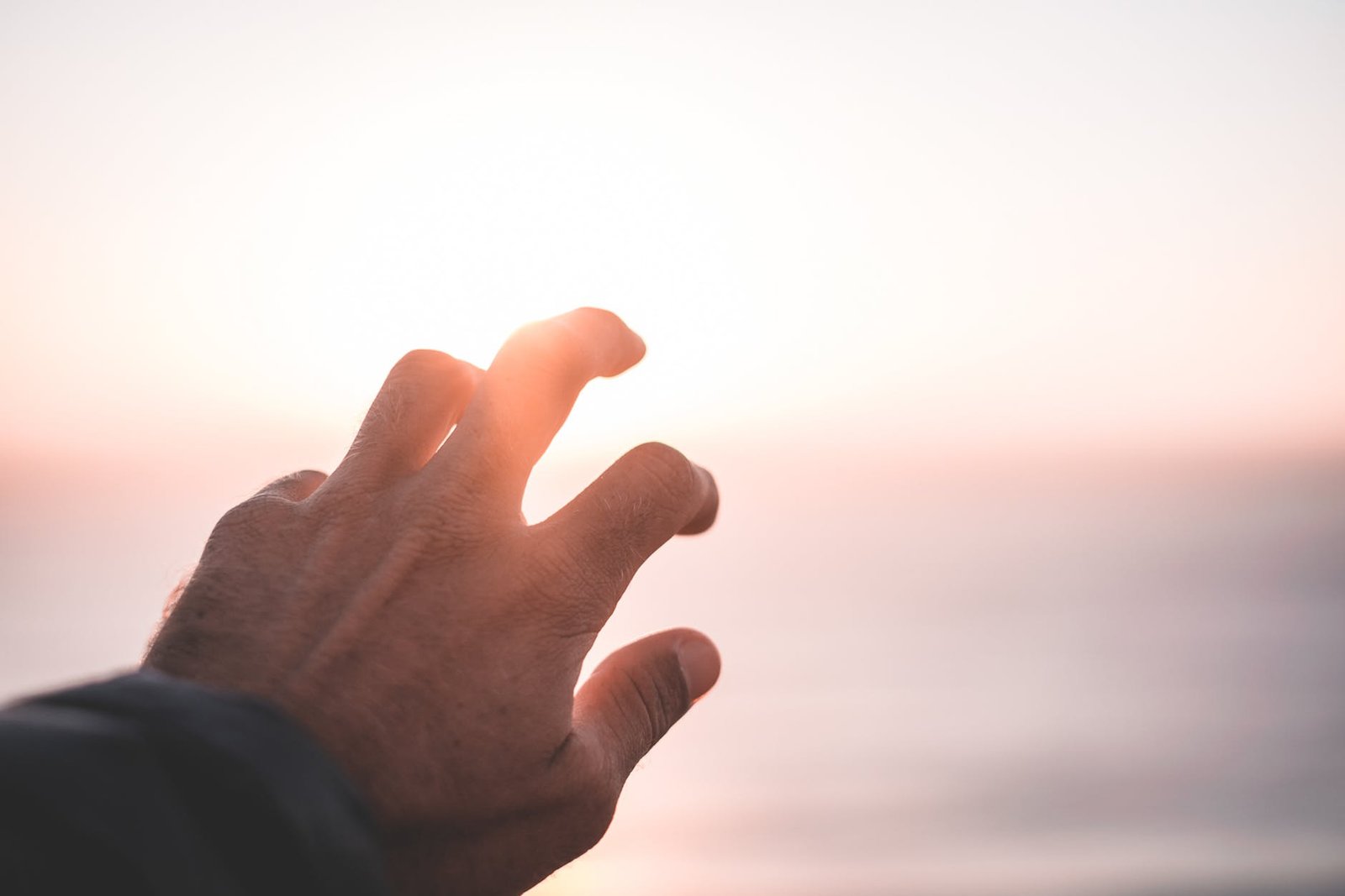 man covering bright sunlight shining on sunset sky