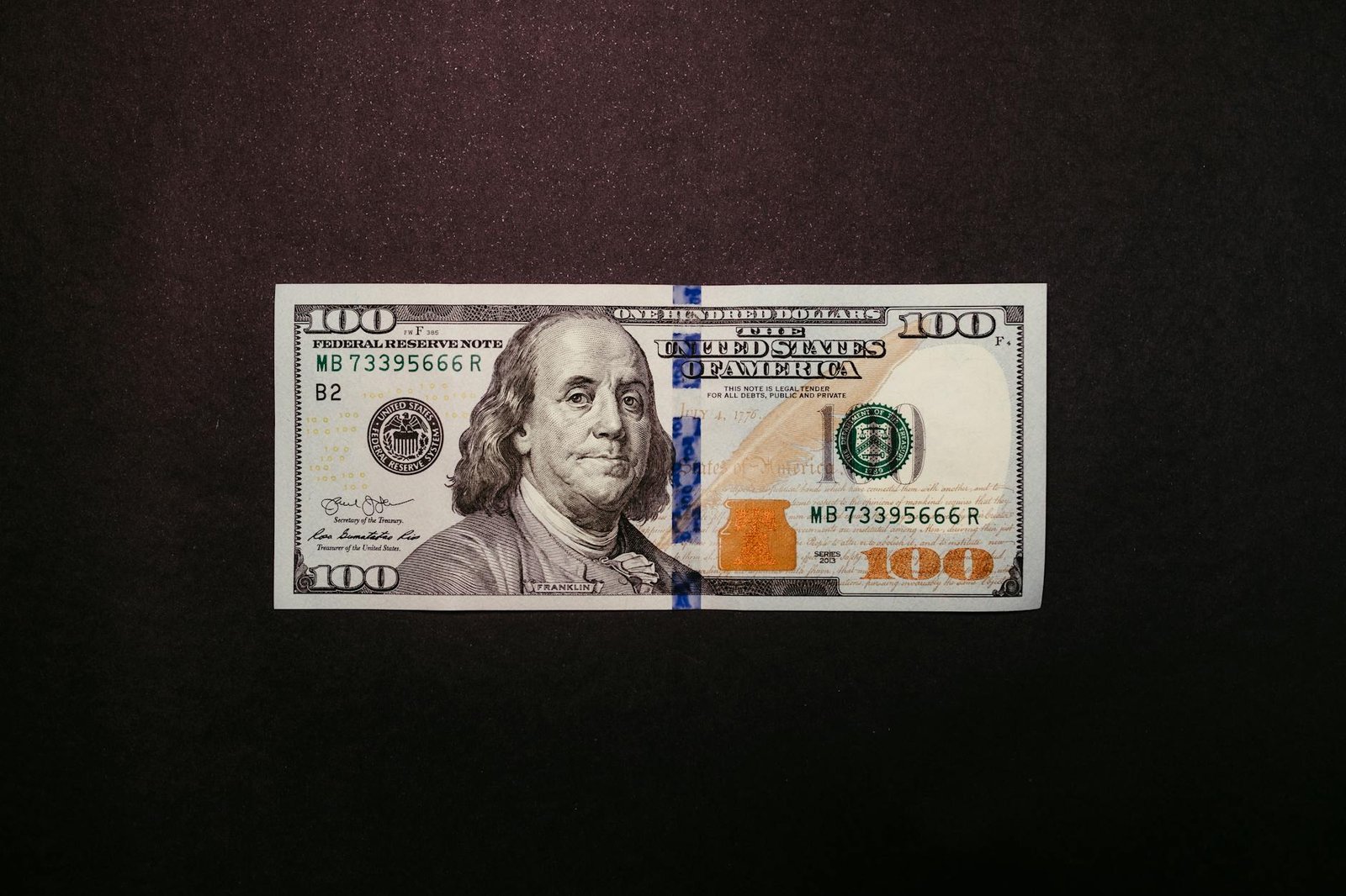 one hundred dollar bill on black background