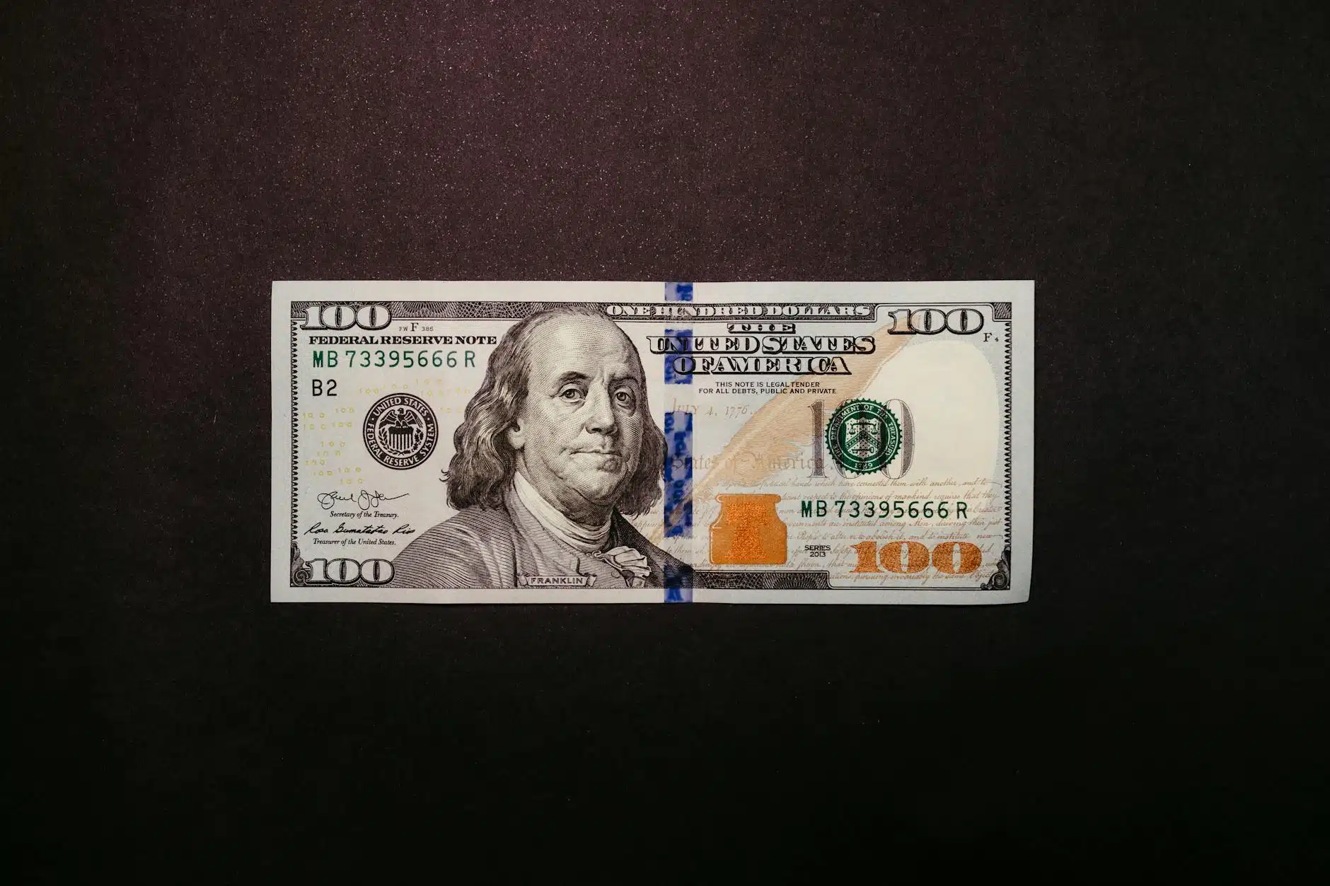 one hundred dollar bill on black background
