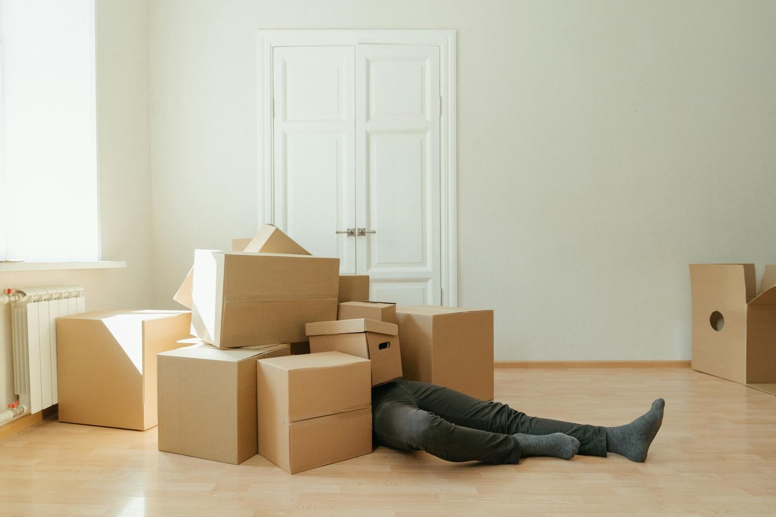 person in black leather boots lying on brown cardboard boxes