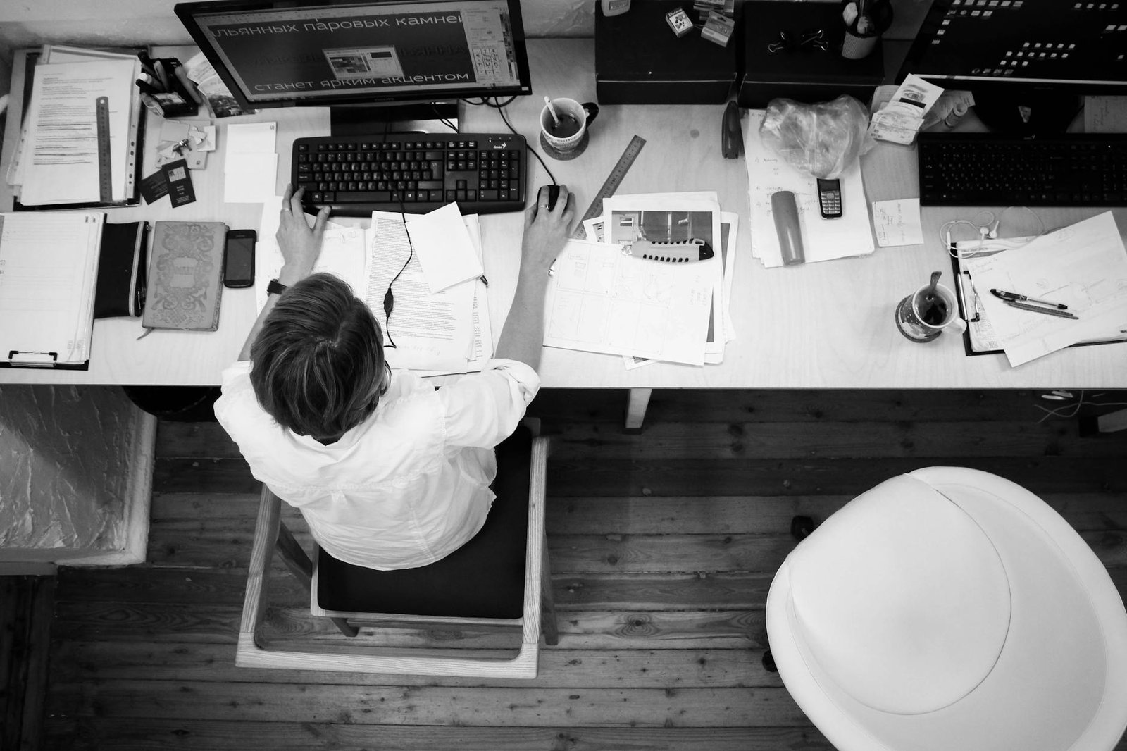 black and gray photo of person in front of computer monitor