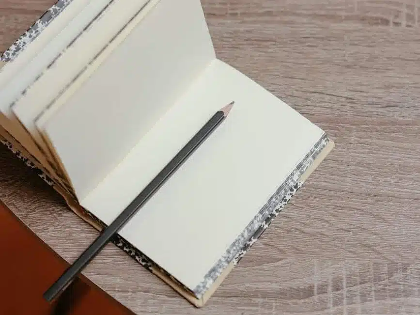 black pencil on white notepad near cup of coffee