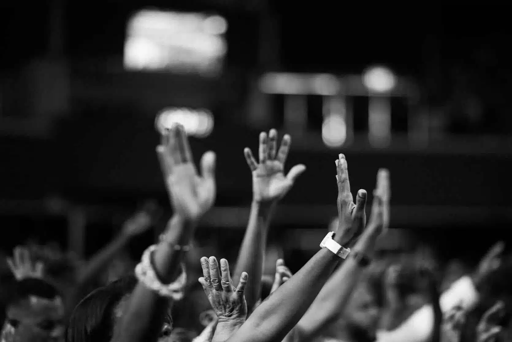 grayscale photography of people raising hands