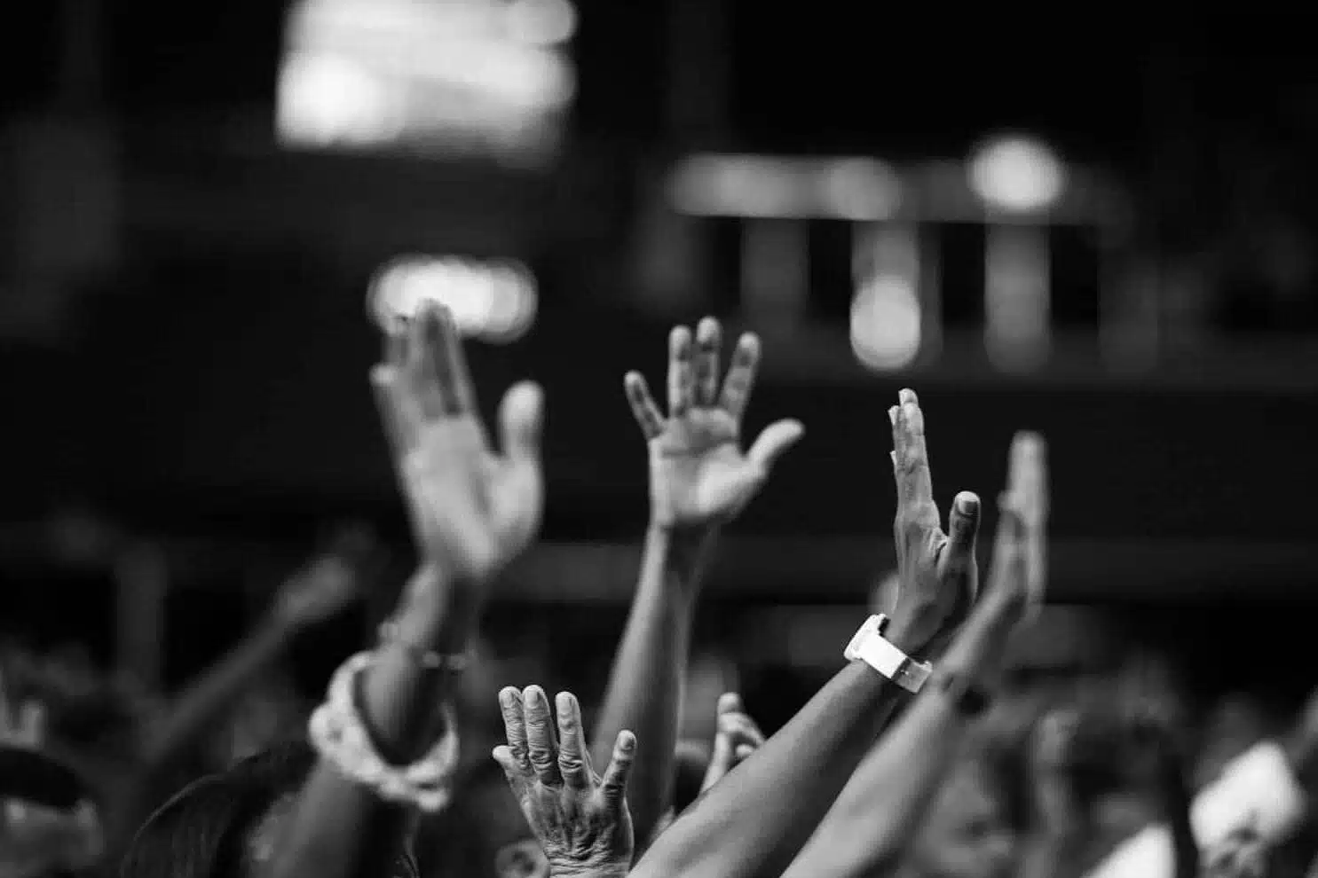 grayscale photography of people raising hands