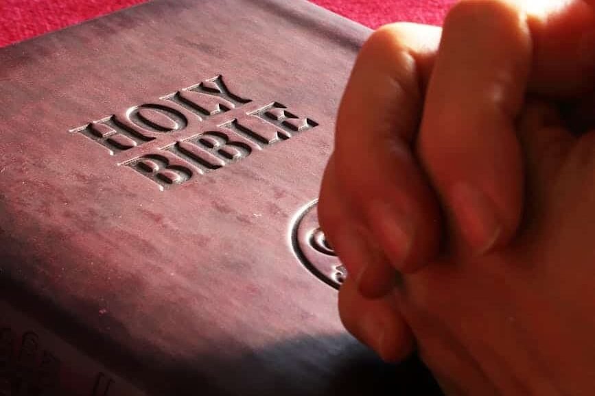 person hands on holy bible